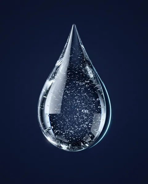 Goutte de sérum transparente parsemée de paillettes.